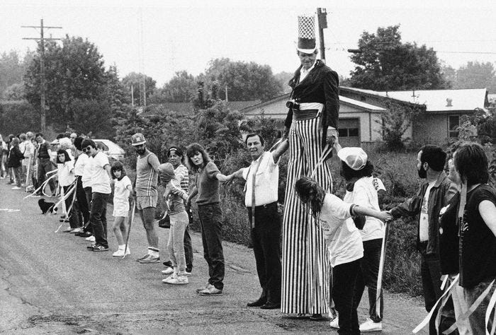 Uncle Sam, also known as Joe Bowen, of Louisville, Kentucky joins hands with other Hands Across America participants in rural Shelby County, Indiana on Sunday, May 26, 1986. Bowen and about seven other stiltwalkers joined in the effort to help America’s needy. (AP Photo/MAC)