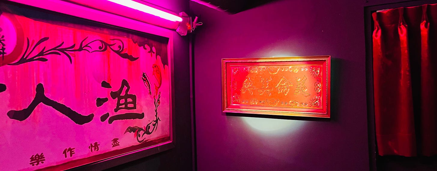 Chinese calligraphy hangs on purple walls under neon pink lighting at the bar Dau 島 in Taipei's Da'an district