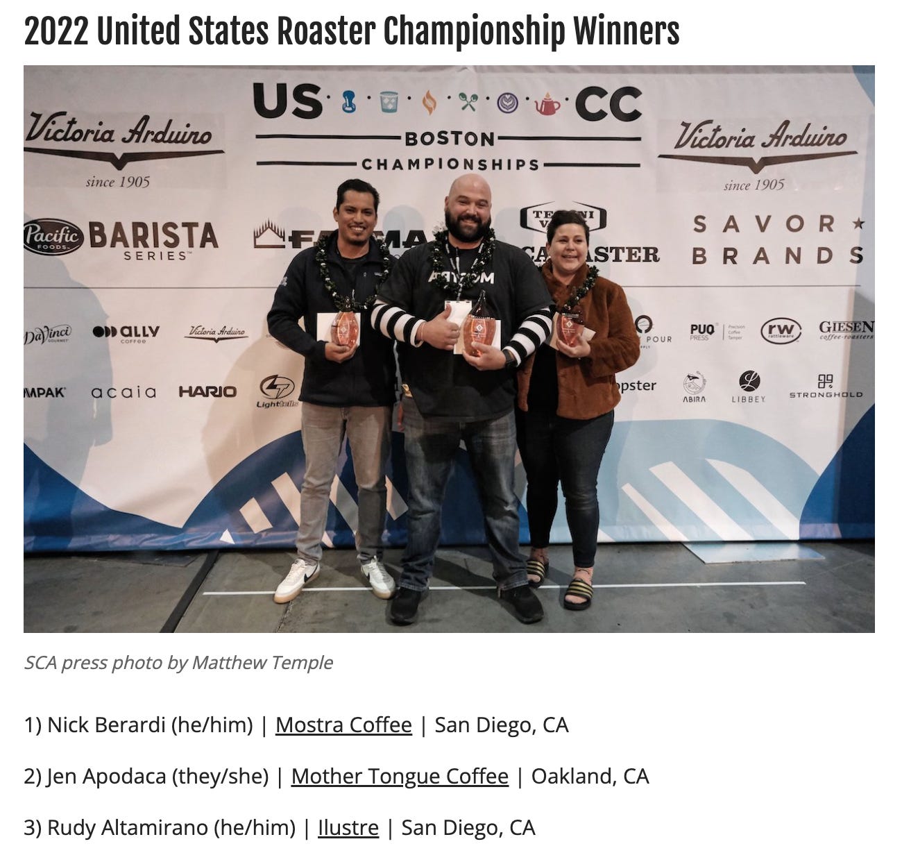 The three winners stand in front of a promotional banner for the SCA Roaster Championships holding trophies.