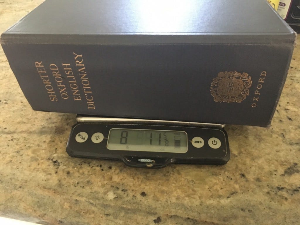 An Oxford English dictionary on a scale, showing it weighs 8 lbs, 11oz