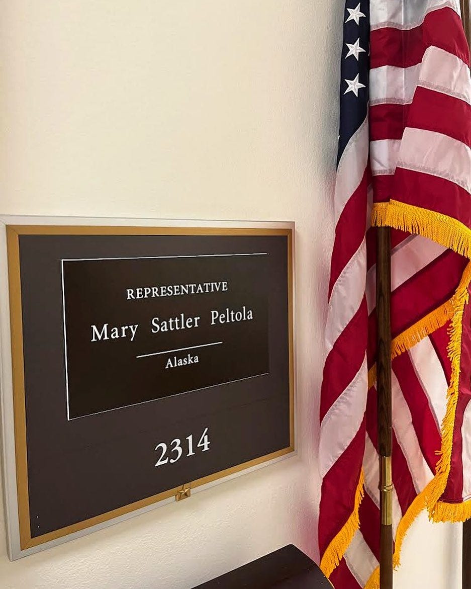 Congresswoman Mary Peltola's name plate on the wall outside her office next to an American flag.