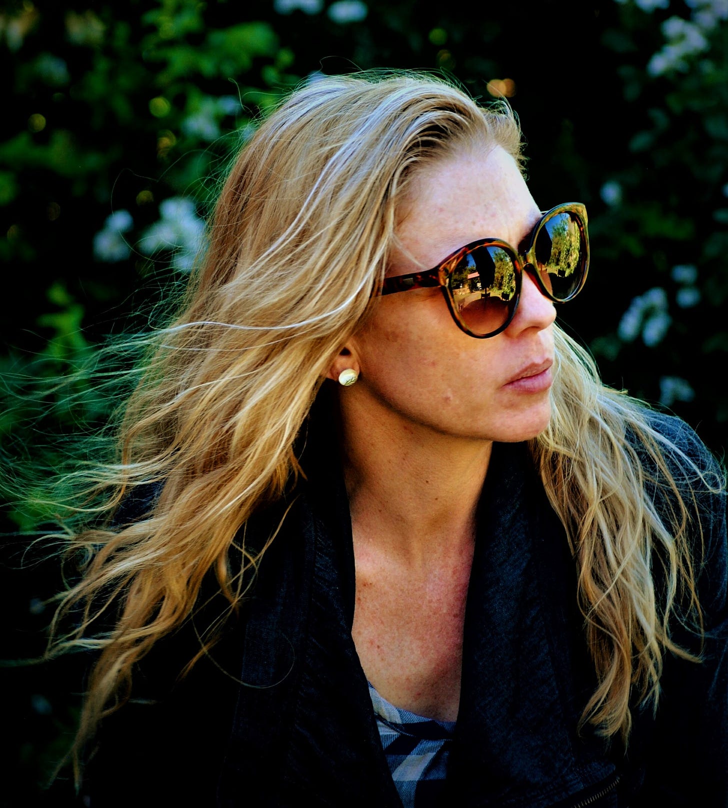 woman with long blonde hair wearing sunglasses looking to the side 