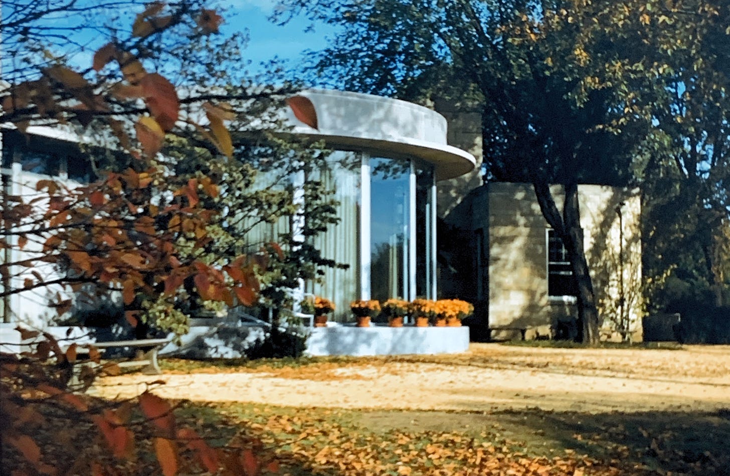 Another angle showing the circular windowed pavilion, from slightly behind the fall leaves of a tree.