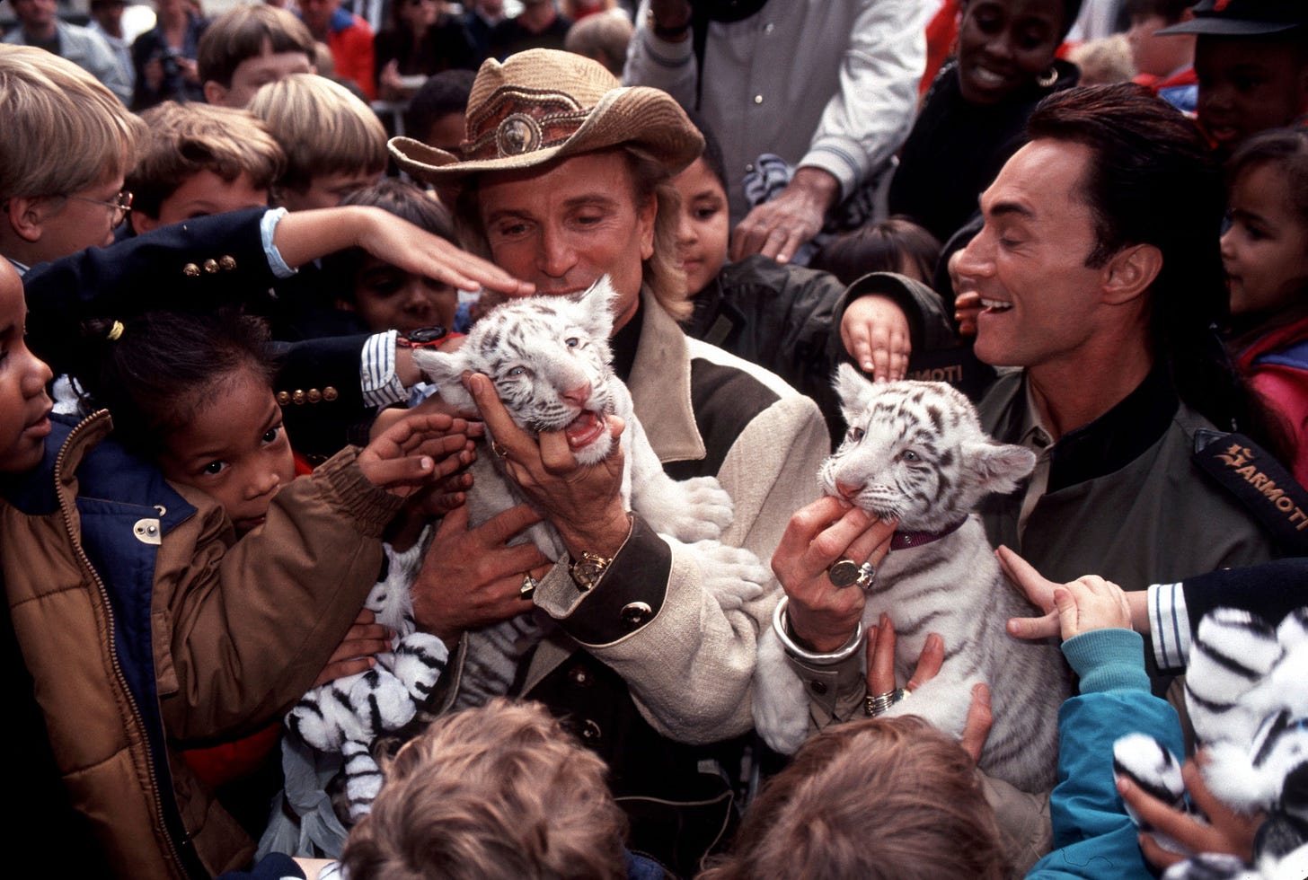 Siegfried & Roy with two small tigers in a crowd