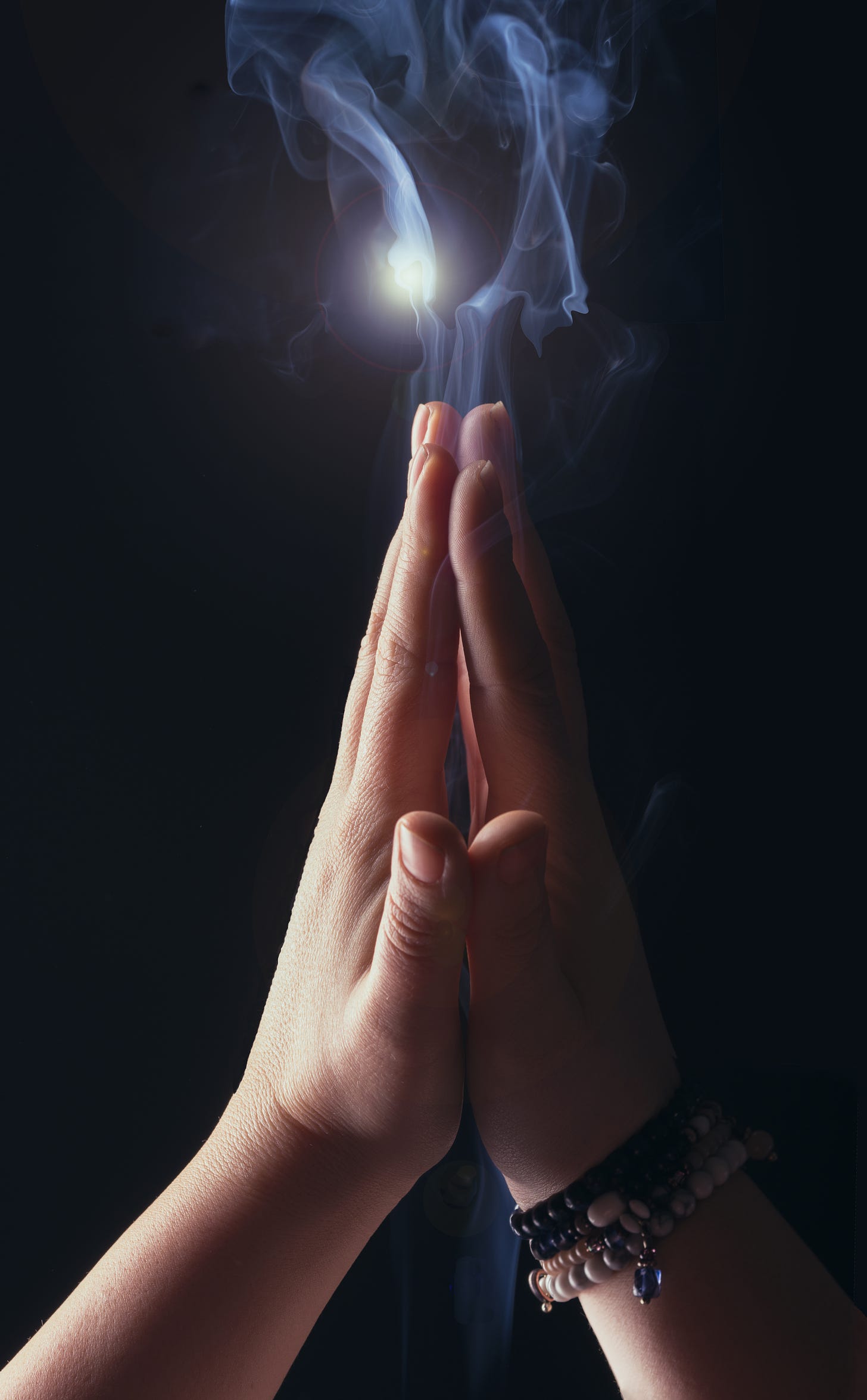 Two hands, raised, palm to palm, creating the illusion of smoke (actually, that seems to be Photoshopped in) with an eerie light source behind it