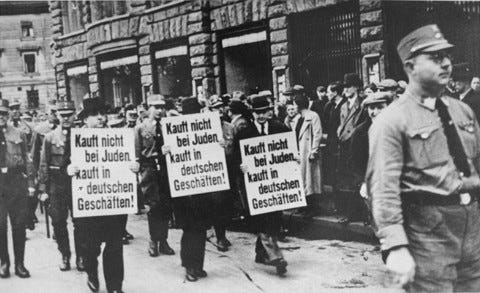 <p>Three Jewish businessmen are forced to march down a crowded Leipzig street while carrying signs reading: "Don't buy from Jews. Shop in German businesses!" Leipzig, Germany, 1935.</p>