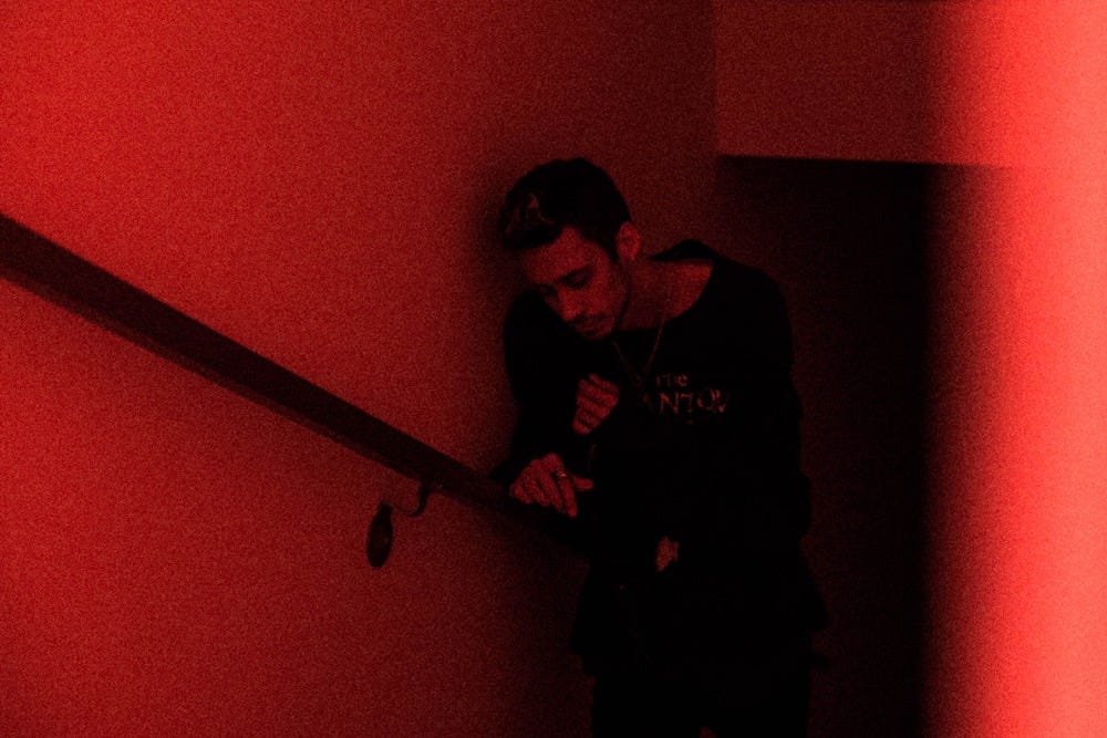 cøzybøy posing at the bottom of a dark stairwell. The photo is lit in red.