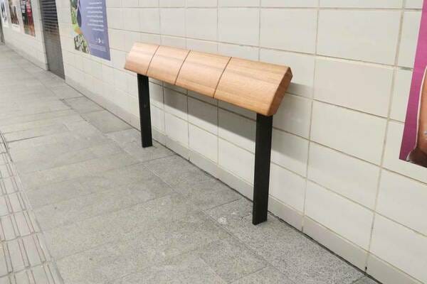 A leaning bench in a public place. This is a board at approximately ass-height pitched at a 75° angle.