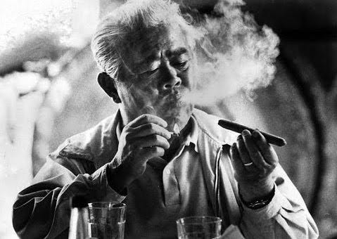 an older James Wong Howe with white hair smoking a cigar