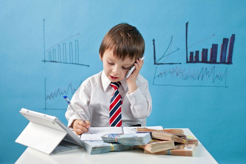 A child in a tie taking a call while doing work.