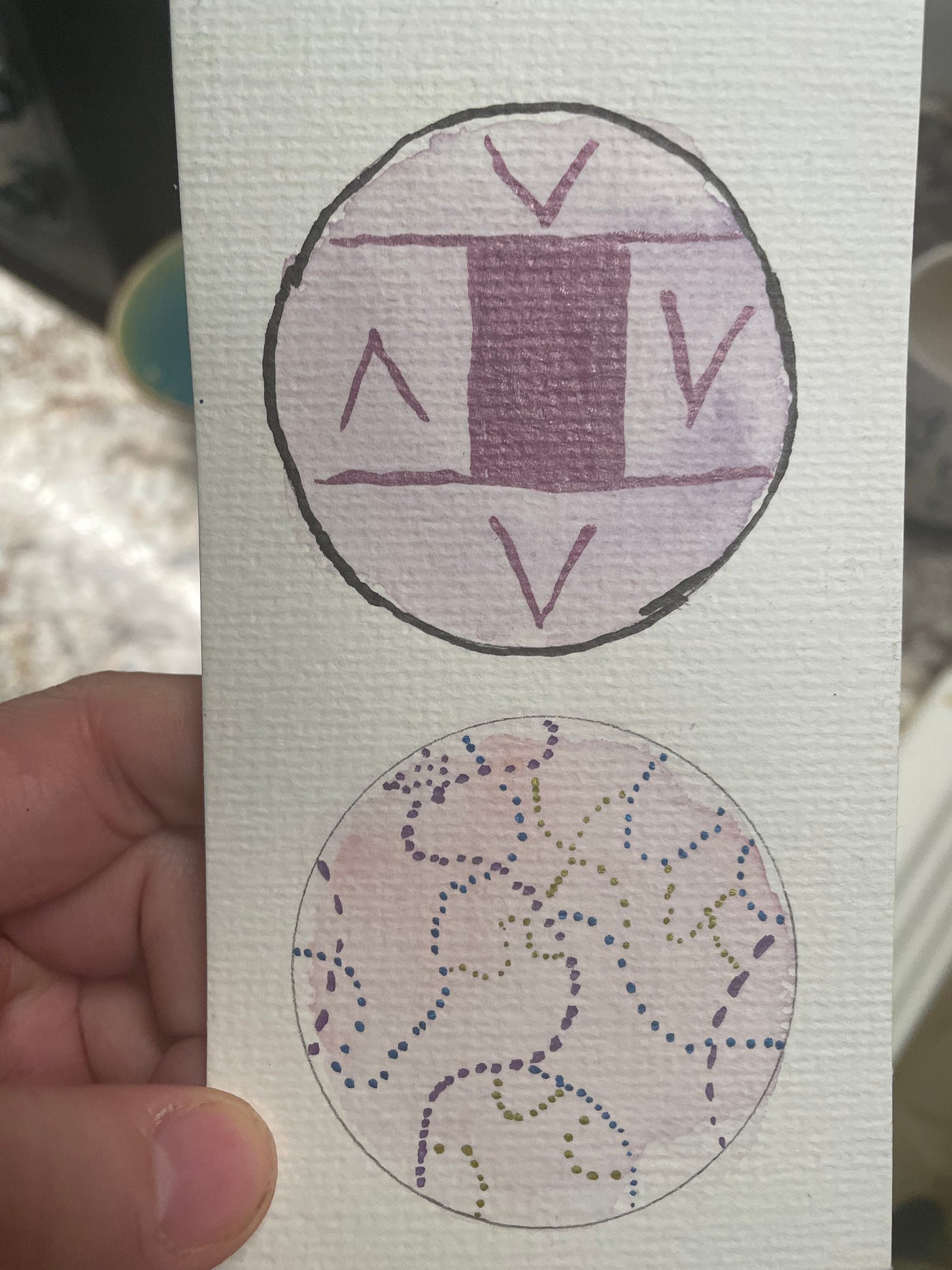 A piece of paper with 2 circles with various shades of pink and different marks on top of them