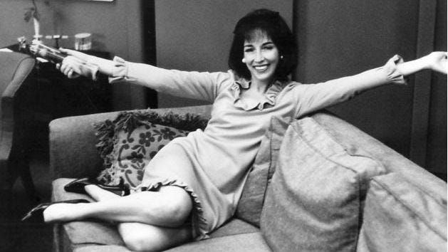 Helen Gurley Brown, sits on a sofa