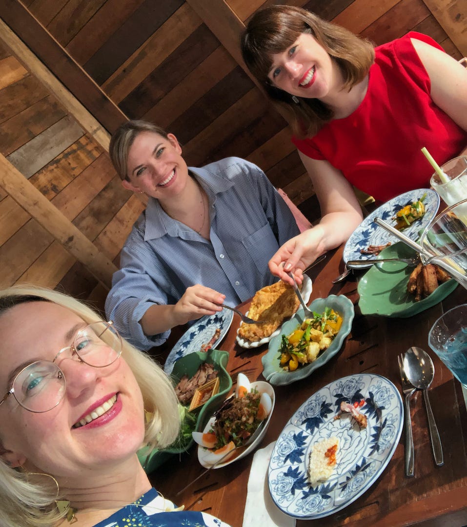 Three friends at a table filled with food