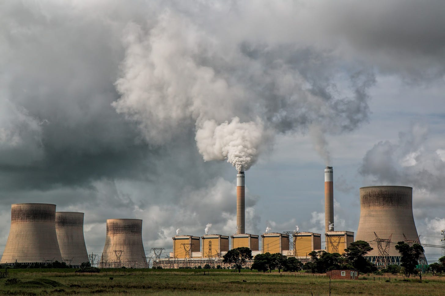Photo of a power station with a chimney sending grey smoke into the sky