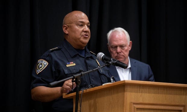 A man in a police uniform speaks into a microphone attached to a lectern.