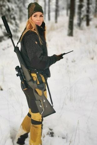 Hunter Erica Egonsson walks through a forest with a rifle over her shoulder