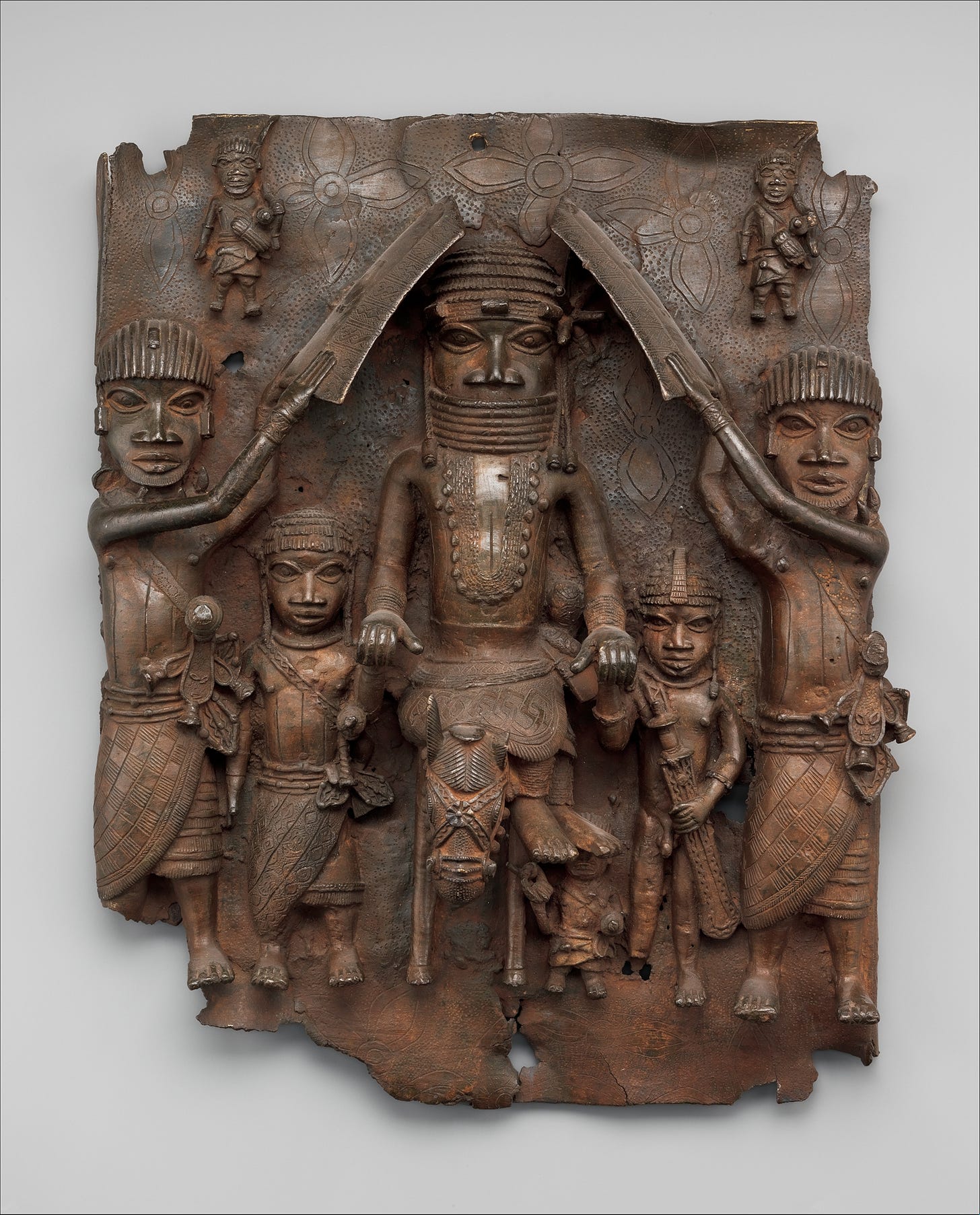 A king on horse is flanked by attendants, progressively smaller to indicate diminished stature in this brass relief artwork.