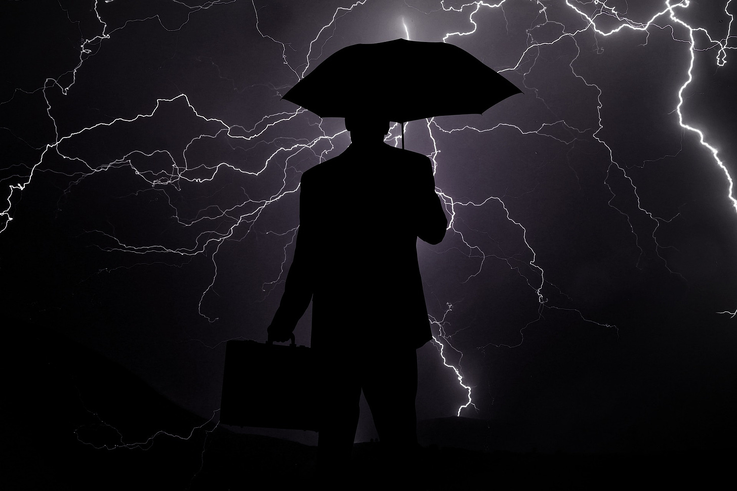 Picture of business man caught in a storm, holding an umbrella