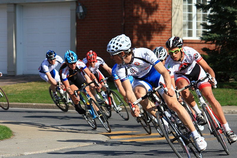 A pack of cyclists leaning at a sharp angle as they corner during a race.