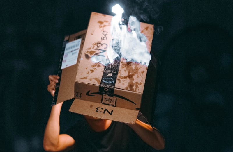 A man lights a cardboard Amazon box on fire.