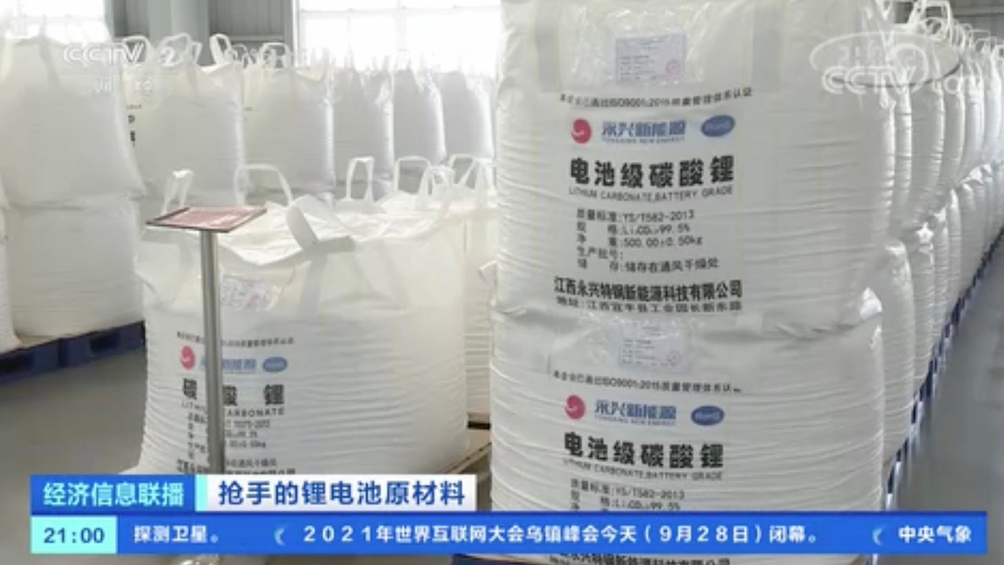 A screenshot of a news segment produced by China's CCTV network. The image shows rows upon rows of sterile-looking white bags containing lithium carbonate sitting on a factory floor