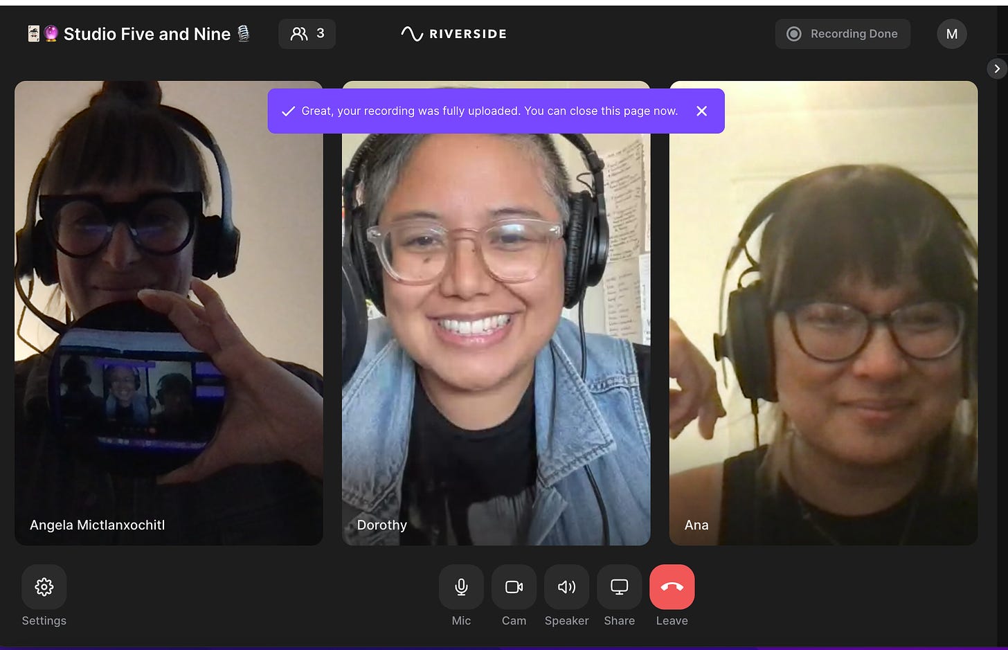 Image description: A screenshot (from left to right) of guest, Angela, and co-hosts, Dorothy and Ana in rectangular boxes within our digital podcasting studio, Riverside, smiling for the camera. Angela is holding her obsidian mirror to the screen.