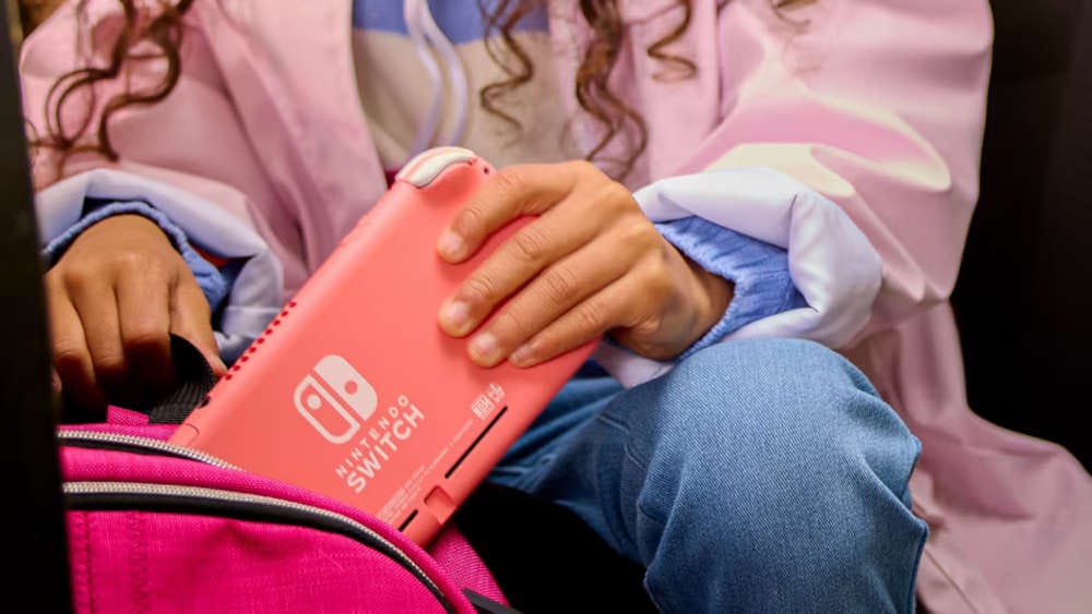 A person putting a Nintendo Switch Lite into a backpack