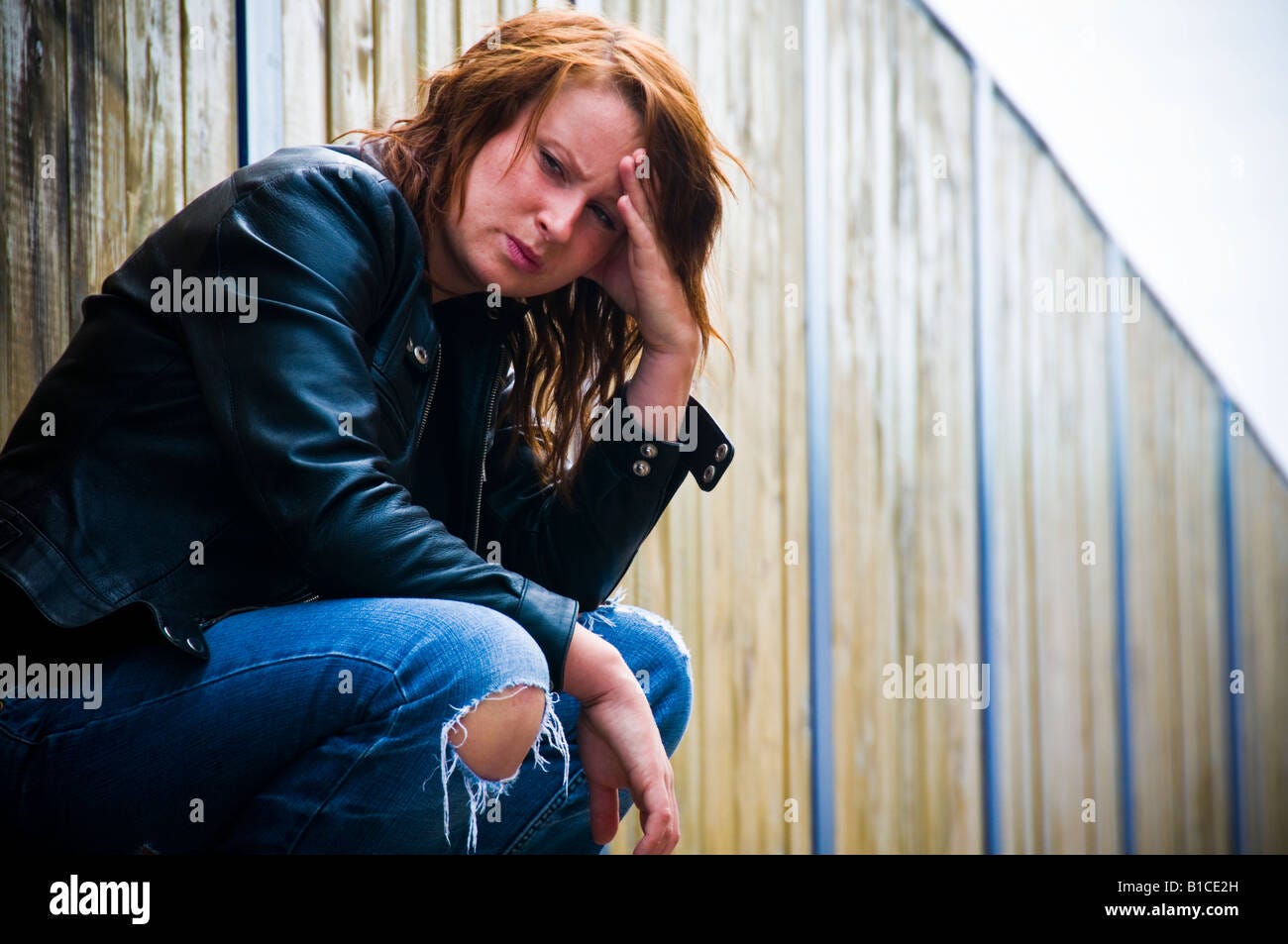 young redhead red haired woman girl worried anxious depressed sad alone  lonely crouched down wearing leather jacket outdoors Stock Photo - Alamy