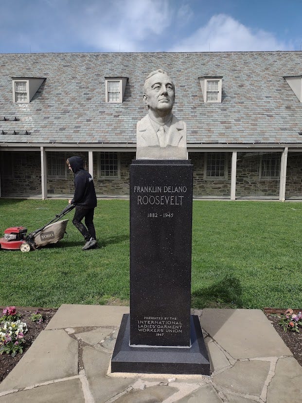 Part of FDR museum with bust of FDR and man mowing lawn behind