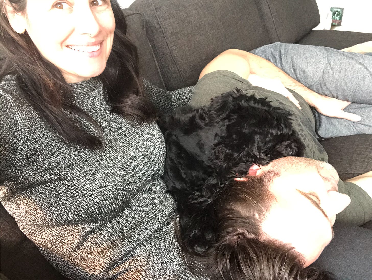 Woman smiling at camera while a guy and dog sleep in her lap