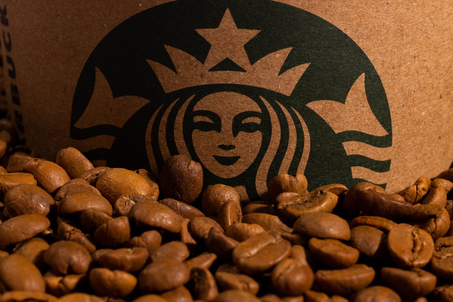 a close up of the green starbucks siren on a cardboard background with coffee beans