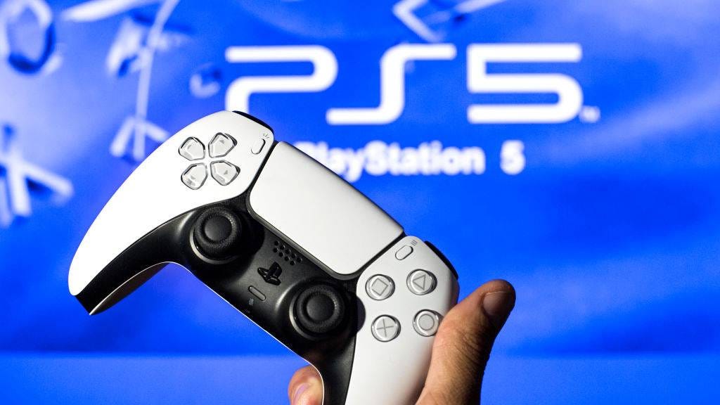 Man holding a PS5 DualSense against a PlayStation background