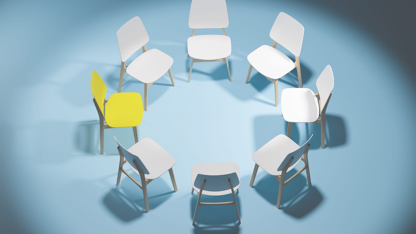 Empty chairs arranged in a circle in a dark studio room