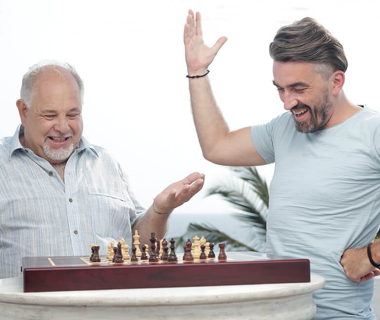 Two white men marvel at the Square Off chess board.
