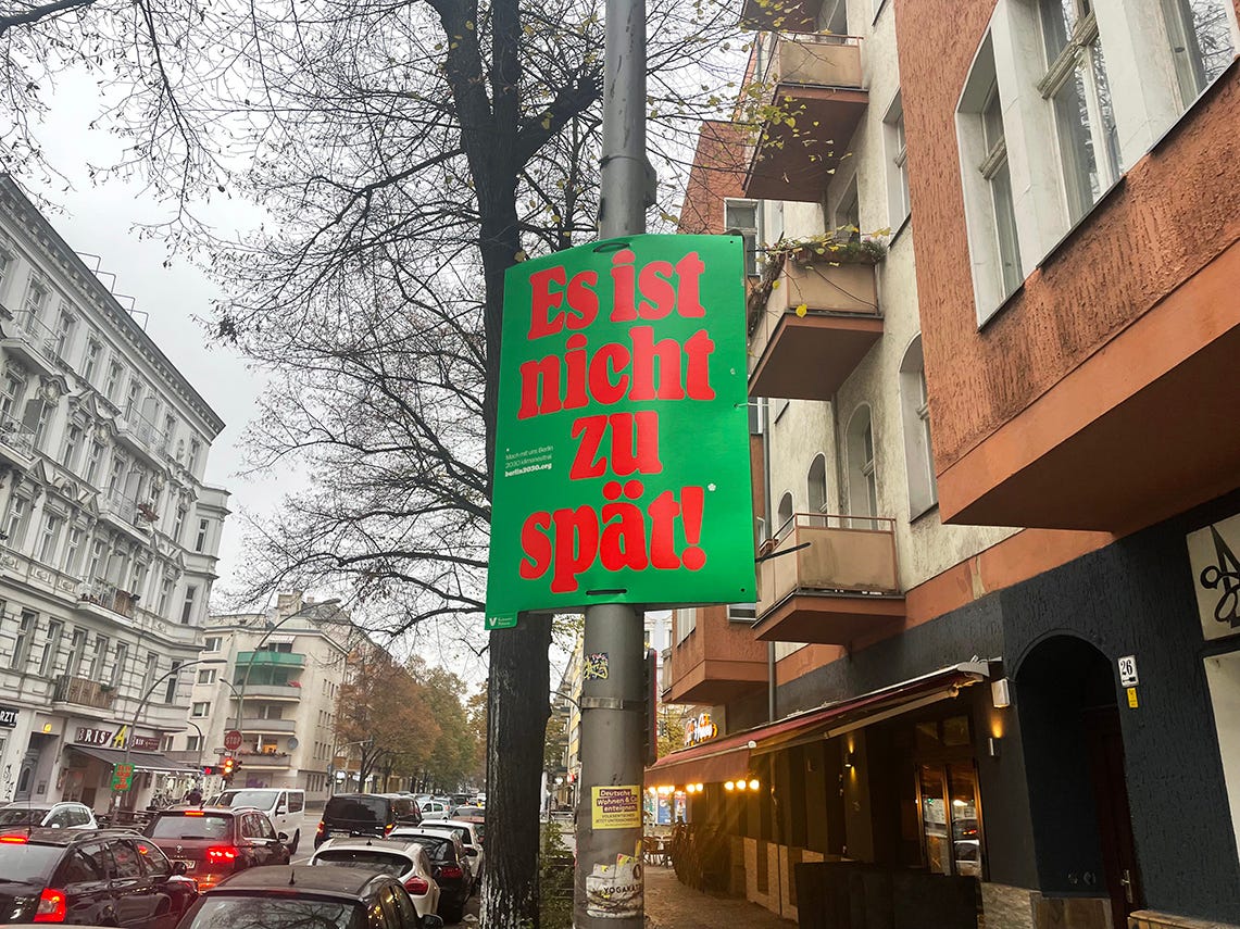 A placard is fixed to a light pole in a street in Berlin. It reads, "Es ist nicht zu spät" (It's not too late)