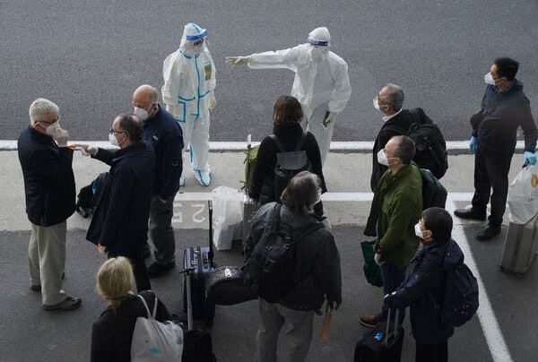 Workers in protective clothing greeting members of the World Health Organization team at the airport in Wuhan, China, on Thursday.