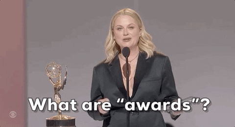 GIF: Amy Poehler stands next to an Emmy, and asks, "What are 'awards?'" while making quotation marks with her fingers