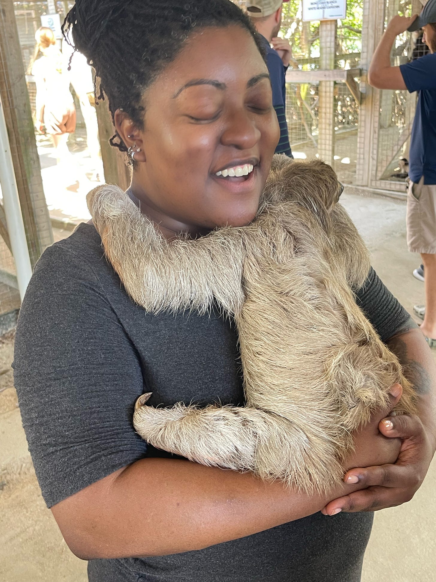 A nonbinary Black person holding a slot at an animal sanctuary 