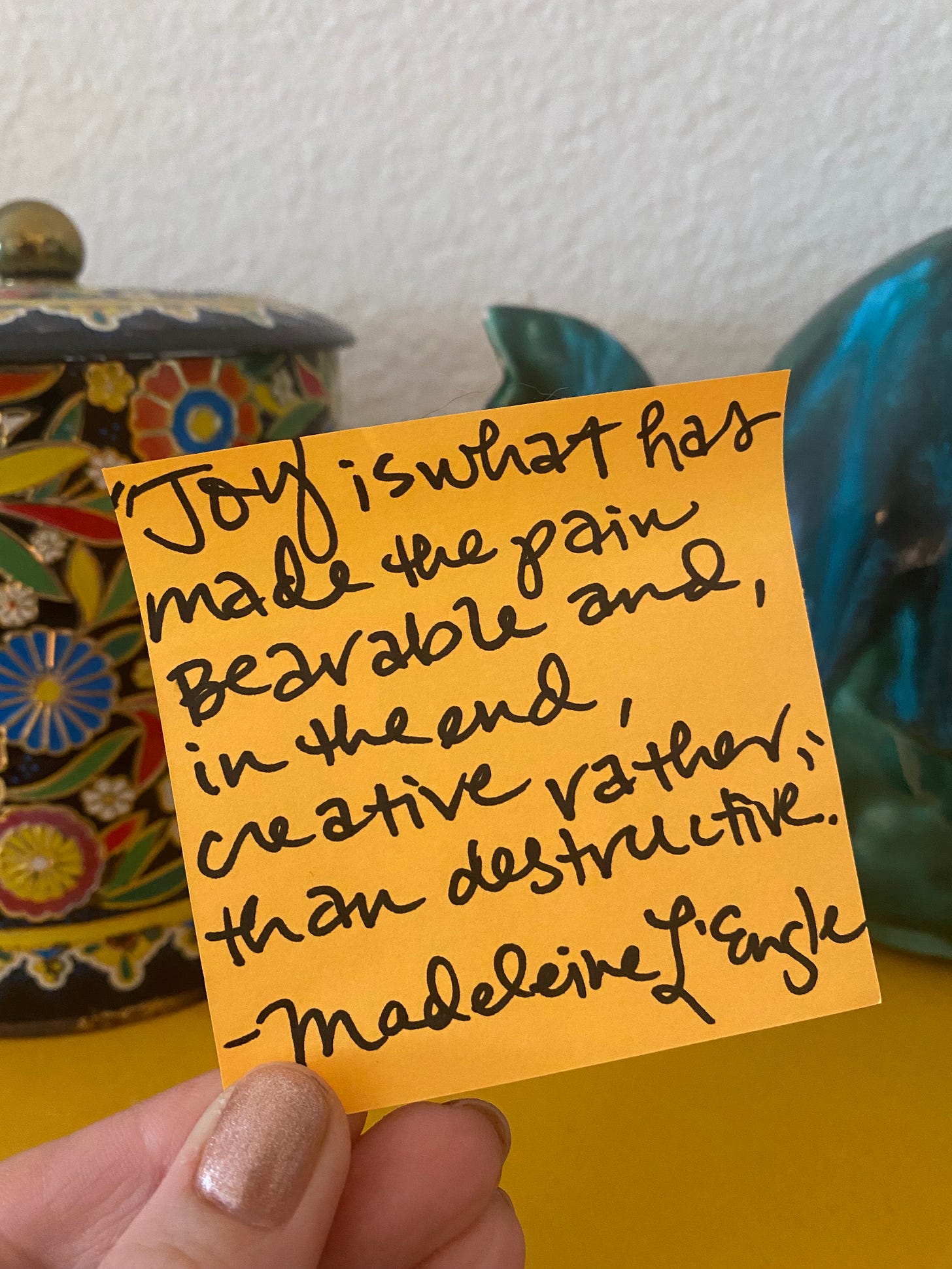 EJW holding today's inspiration in front of a colorful tin and teal teapot on an orange post-it note