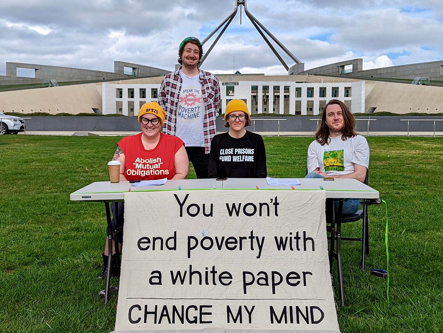 Activists outside Parliament House behind a banner that reads “You won’t end poverty with a white paper”. 