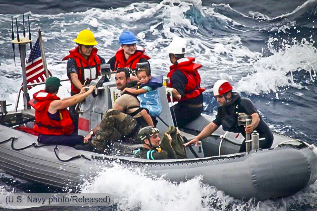 Nine people, including two small children, on a US Navy RHIB amongst high seas in the Pacific Ocean.