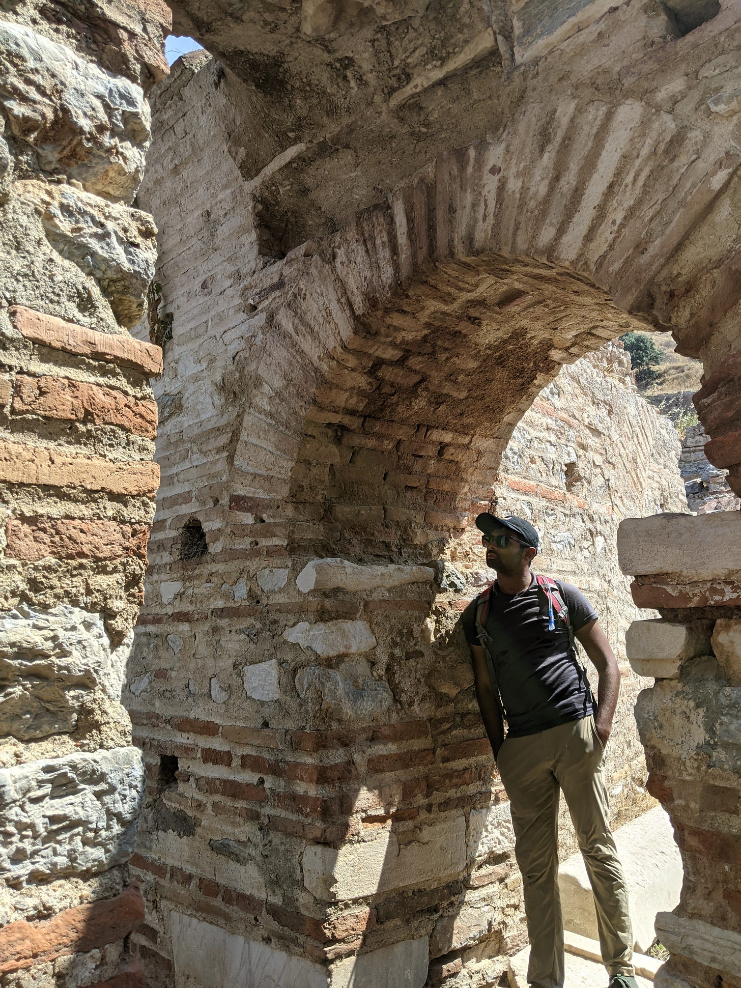 Aseef leaning against an ancient archway in Ephesus that contains Byzantine, Roman and Greek components