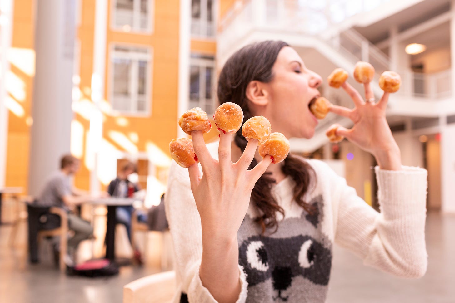 Girl in racoon sweater with donut holes on her fingers
