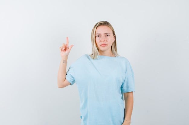 Free Photo | Blonde girl showing hold on a minute gesture in blue t-shirt  and looking serious , front view.