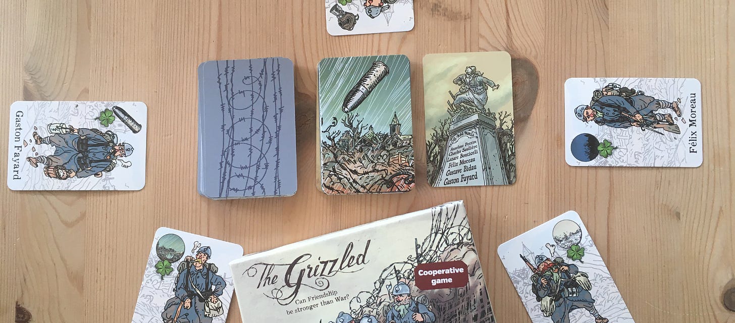 The Grizzled game laid out informally, stacks of cards in the middle revealing a monument, player cards around the side.