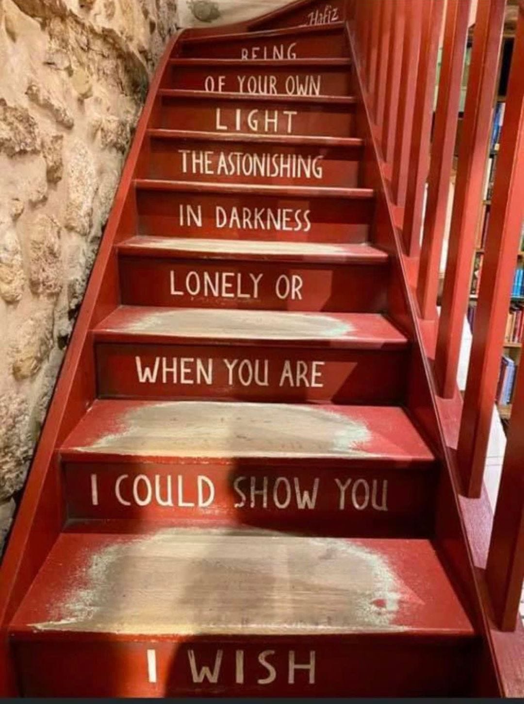 Red painted, worn wooden stairs with the Hafiz quote painted on them