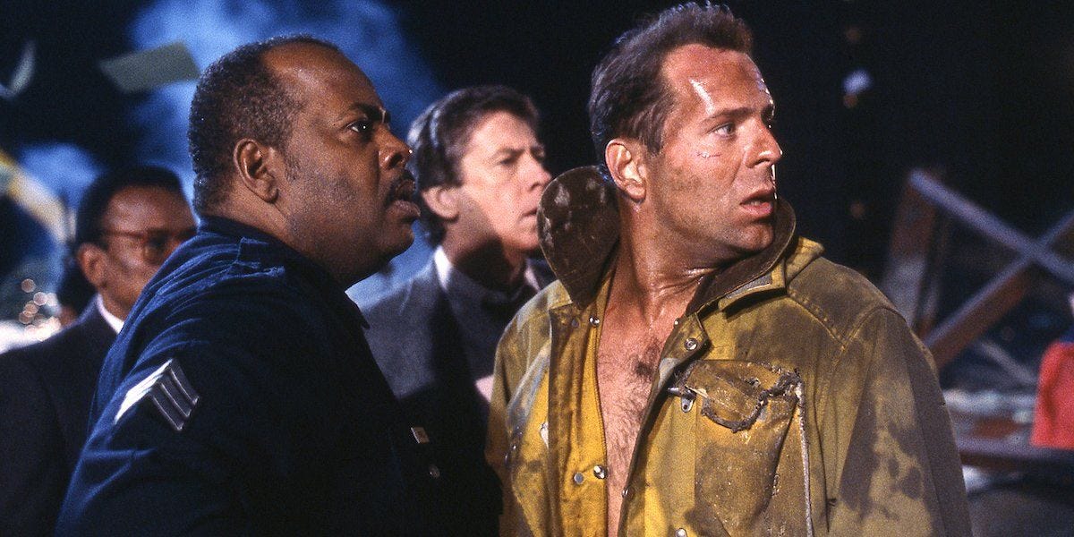 Al Powell and John McClane in the film Die Hard, looking to the right of the frame with shocked expressions on their faces