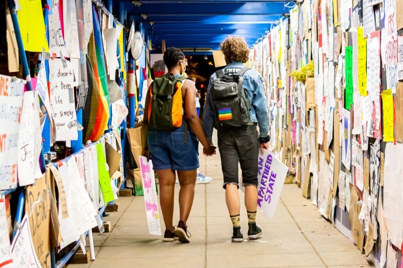 Two activists walking down a hallway covered with signs.