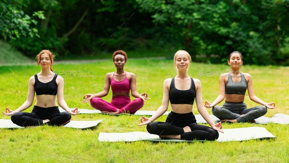 Outdoor yoga class. Group of diverse girls doing breathing exercises or  meditation in nature Stock Photo by Prostock-studio