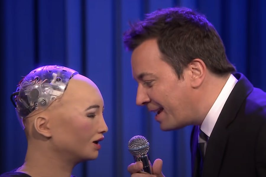 Imagem mostra frame de um vídeo em que a robô com traços humanóides Sophia, do MIT, canta uma música de Cristina Aguilera em dueto com o apresentador Jimmy Fallon, no programa dele, The Tonight Show, em 2018.